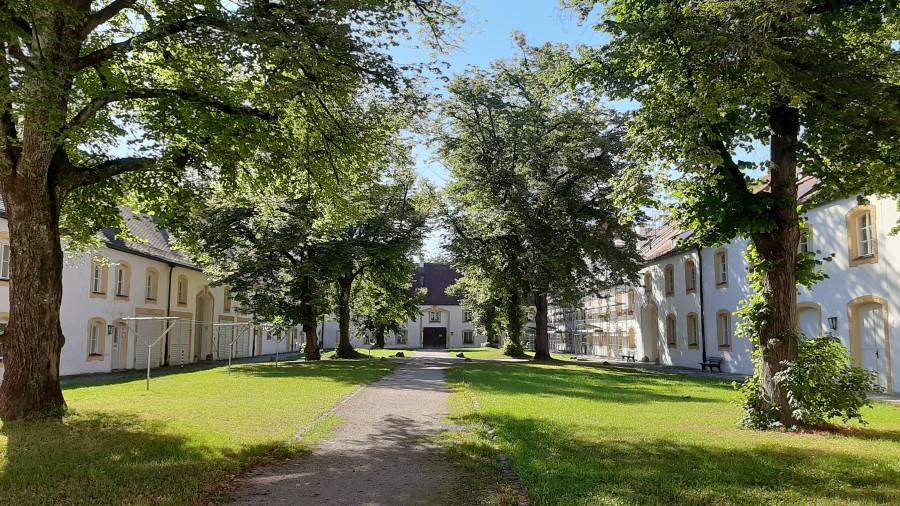 Sonniger, baumbestandener Innenhof mit Häusern im Schmiedehof Nymphenburg