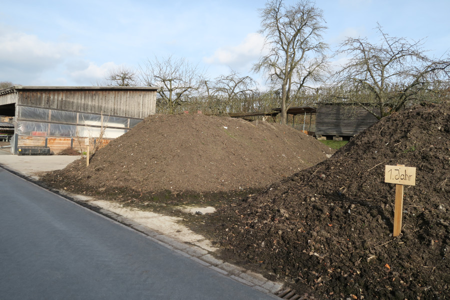 Zwei große Komposthaufen mit einer Holzhalle für Kompost im Hintergrund bei der SGV Bayreuth