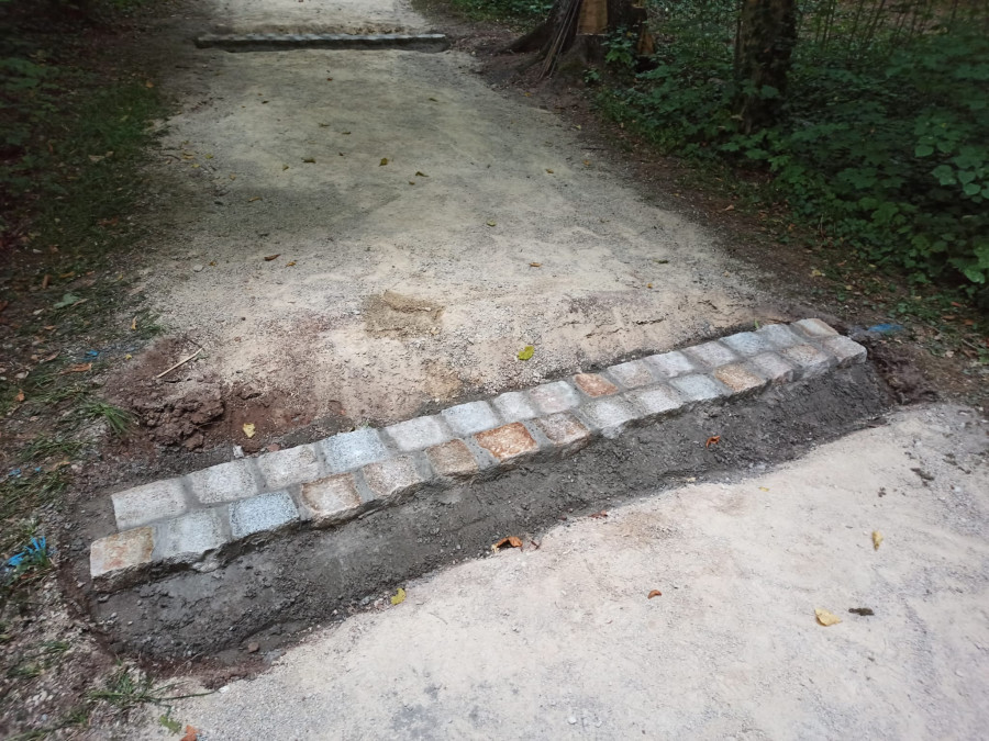 Fertiggestellter Einbau einer Querrinne aus Granitquadersteinen auf dem Weg im Park Rosenau. Diese dient zur Entwässerung der Wege nach Regenfällen